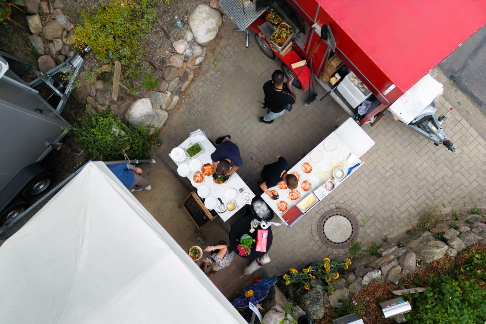 Vogelperspektive auf Foodtruck und Ausgabetische bei einer Gartenveranstaltung