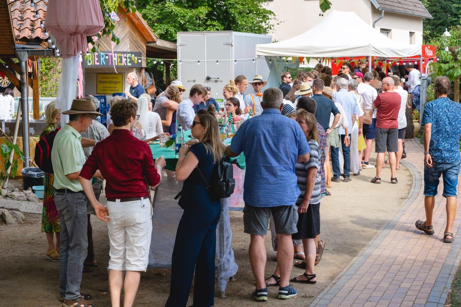 Gäste warten bei einem Sommerfest in der Schlange an Bierstand und Foodtruck