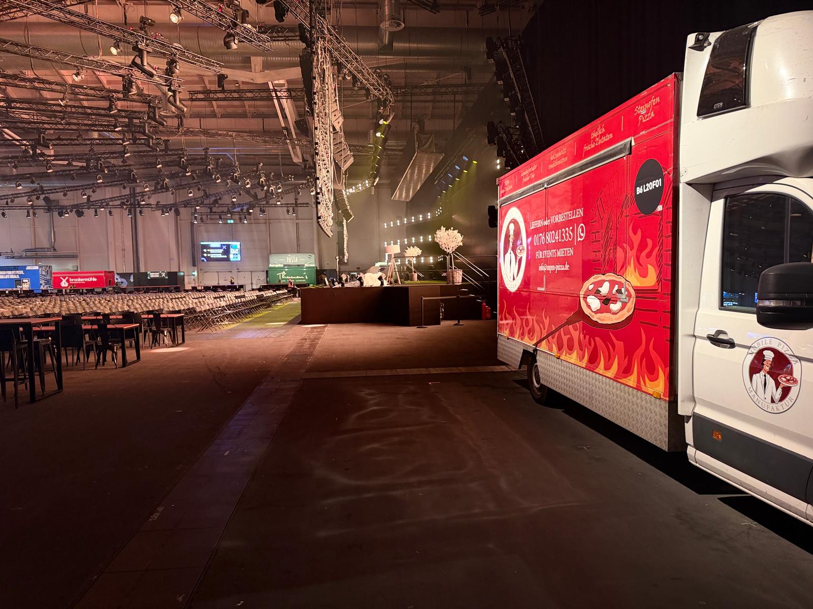 Foodtruck in einer großen Veranstaltungshalle mit Bestuhlung im Hintergrund
