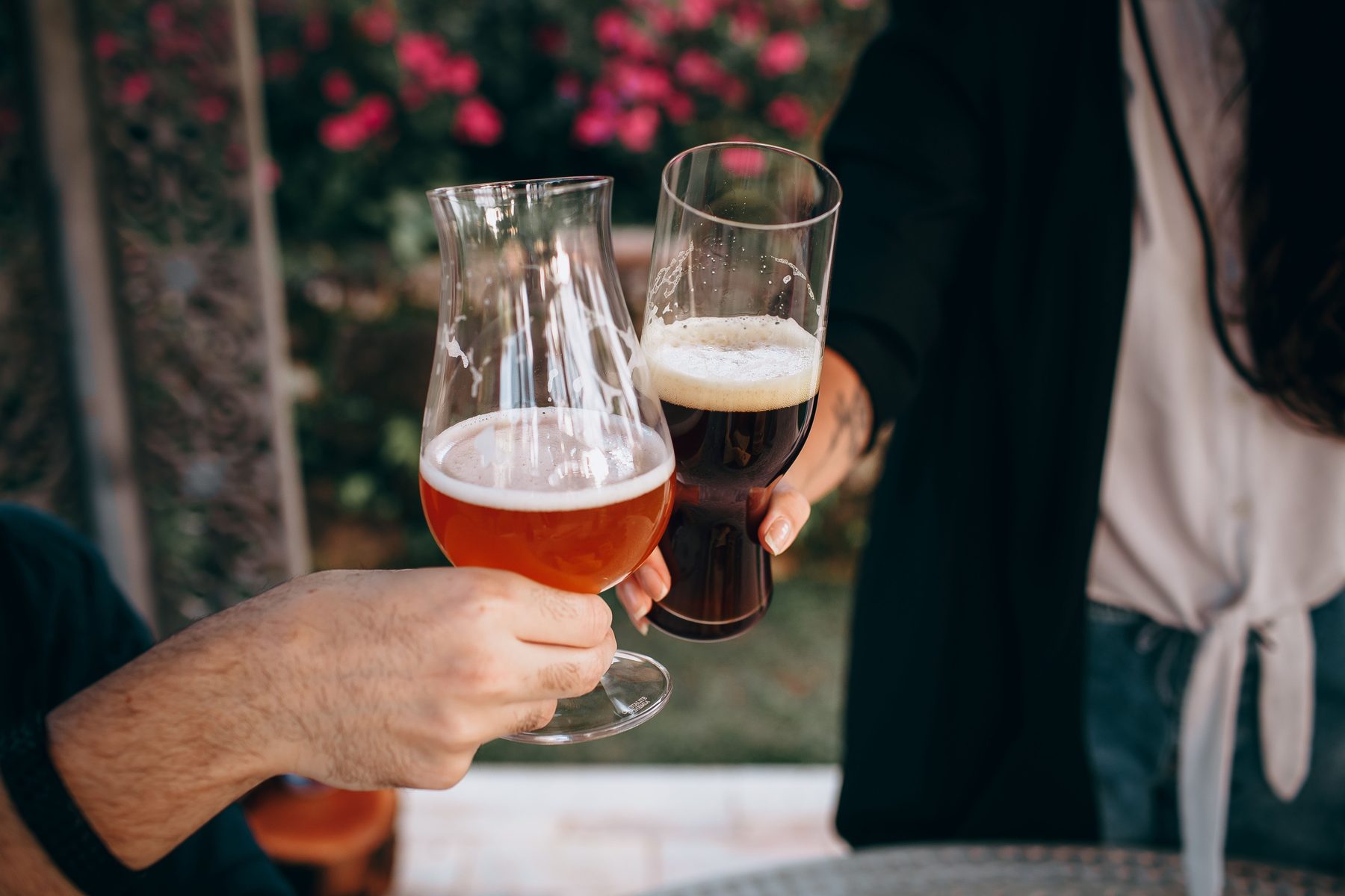 Zwei Biergläser stoßen im Freien an