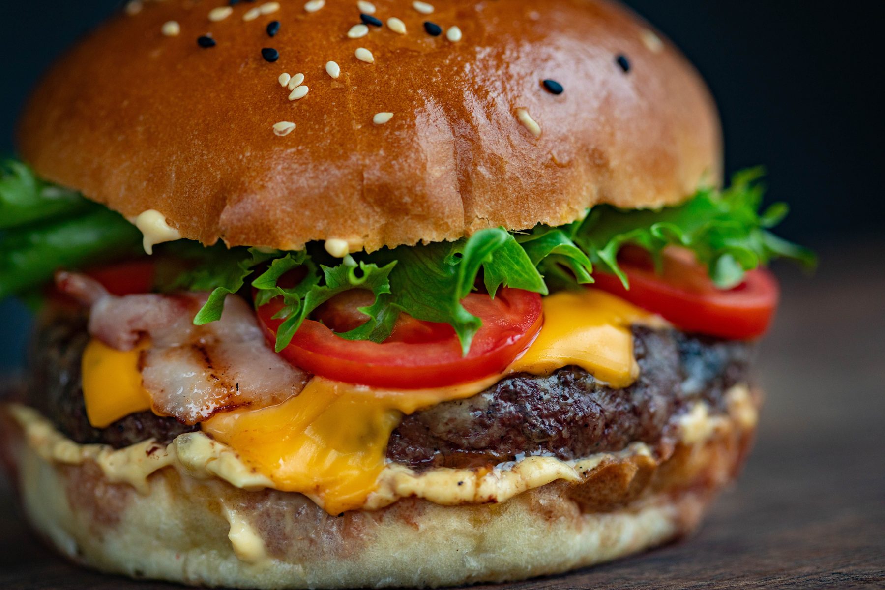 Saftiger Burger mit Bacon, Käse, Tomate und Salat in Nahaufnahme