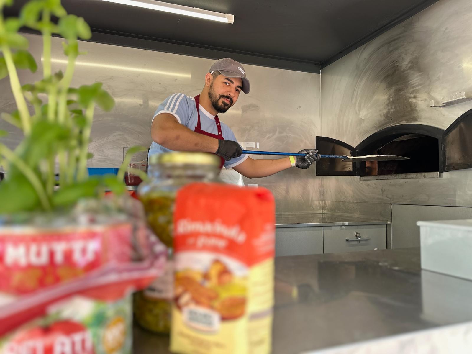 Pizzabäcker schiebt eine Pizza in den Ofen des Foodtrucks