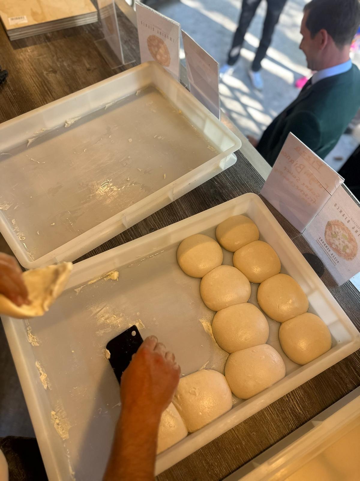 Hand teilt frische Teiglinge im Gärkorb für die neapolitanische Pizza